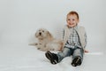 A little boy is sitting, playing with a white dog Royalty Free Stock Photo