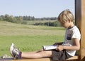 Little boy sitting and reading book at summer terrace. Casual clothes. Nature background. People, education, knowledge Royalty Free Stock Photo