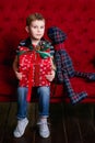 Little boy sitting on the red coach with christmas present in his hands Royalty Free Stock Photo