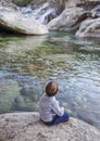 Little boy sitting at riverside of Los Pilones Gorge at Natural Reserve Garganta de los Infiernos