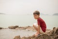 Little boy sitting on the rock on the beach face look happy Royalty Free Stock Photo