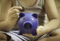 Little boy sitting, saving blue piggy bank in hand, concept of financial planning for education, saving and depositing money in Royalty Free Stock Photo