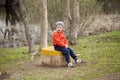 Little boy sitting on a stump in the spring park Royalty Free Stock Photo