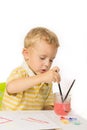 Little boy sitting at the table, draws and dunks brush Royalty Free Stock Photo