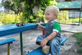 The little boy sitting at a table in the park.