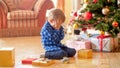 Little toddler boy sitting under Christmas tree and crying