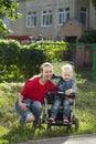 A little boy sitting in a wheelchair and walking with his mother Royalty Free Stock Photo