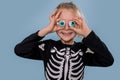 Little boy in skeleton costume holding toy eyeballs over his eyelids