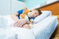 Little boy sleeping in hospital bed with teddy bear Royalty Free Stock Photo