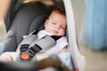 a little boy sleeps strapped in a stroller.