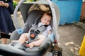 a little boy sleeps strapped in a stroller.