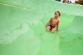 A little boy slides down a green water slide in the water park, a child& x27;s cheerful mood, holidays Royalty Free Stock Photo