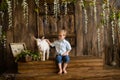 Boy smiles on wooden steps of the porch next to newborn goaling and hugs him