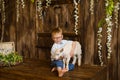 Boy smiles on wooden steps of the porch next to newborn goaling and hugs him