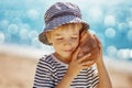 Little boy smiling at the beach in hat andholding shell Royalty Free Stock Photo