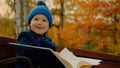 Little boy is smiling with big family album in the autumn park Royalty Free Stock Photo