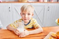 Little boy are smiling while having a breakfast in kitchen. Mom is pouring milk into glass Royalty Free Stock Photo