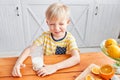 Little boy are smiling while having a breakfast in kitchen. Mom is pouring milk into glass Royalty Free Stock Photo
