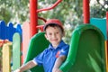Little boy smiling on a playground outdoors in summer. Having fun on a slide. Royalty Free Stock Photo