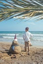 Little boy and Snowmen at tropical ocean beach in santa hat. New Years and Christmas holiday in hot countries concept Royalty Free Stock Photo