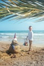 Little boy and Snowmen at tropical ocean beach in santa hat. New Years and Christmas holiday in hot countries concept Royalty Free Stock Photo