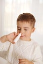 Little boy spraying medicine in nose, nose drops. Toddler child using nasal spray. Runny nose, cold, flu, illness, virus Royalty Free Stock Photo