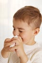 Little boy spraying medicine in nose, nose drops. Toddler child using nasal spray. Runny nose, cold, flu, illness, virus Royalty Free Stock Photo