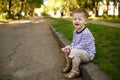 Little boy squints sitting on the curb Royalty Free Stock Photo