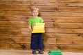 Little boy with stack of books at wooden wall Royalty Free Stock Photo