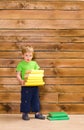 Little boy with stack of books at wooden wall Royalty Free Stock Photo