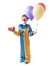 Little boy standing in a clown suit with a red nose and holding a three balloons and a box with a bow