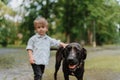 Little boy standing with his big dog in the park. Royalty Free Stock Photo