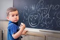 Little boy standing near school blackboard with a piece of chalk Royalty Free Stock Photo