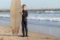 A little boy standing on the seashore with a big surfing board Royalty Free Stock Photo