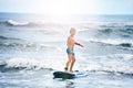 Little boy standing on surf board in the water Royalty Free Stock Photo