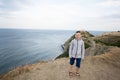 Little boy standing on top of a mountain and looking camera against lighthouse in sea. Cape Emine, Black sea coast, Bulgaria Royalty Free Stock Photo