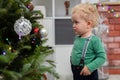 A little boy stands by the Christmas tree and looks at the Christmas decorations Royalty Free Stock Photo