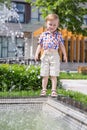 A little boy stands on the fountain in the Royalty Free Stock Photo