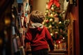 Little boy stands in front of the Christmas tree and looks at the gifts.A child peeking down the stairs to see presents on Royalty Free Stock Photo