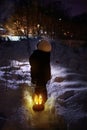 A little boy stands and looks at flying snowflakes. Winter evening. Royalty Free Stock Photo