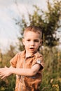 A little boy stands in nature and smiles