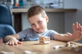 Little boy stands a turret with wooden cubes close up