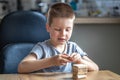 Little boy stands a turret with wooden cubes close up