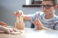 Little boy stands a turret with wooden cubes close up