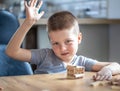 Little boy stands a turret with wooden cubes close up