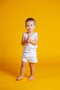 Little boy stands in a white T-shirt and underpants on an orange-yellow background