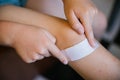 A little boy sticks a Band-Aid on the damaged skin on his leg.An abrasion and a scratch on the knee Royalty Free Stock Photo