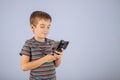 The little boy smiles and looks at the smartphone screen. On a plain blue background with a place to copy Royalty Free Stock Photo