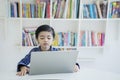 Little boy studying with a laptop in the library Royalty Free Stock Photo