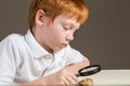 Little boy studying a rock through a magnifying glass